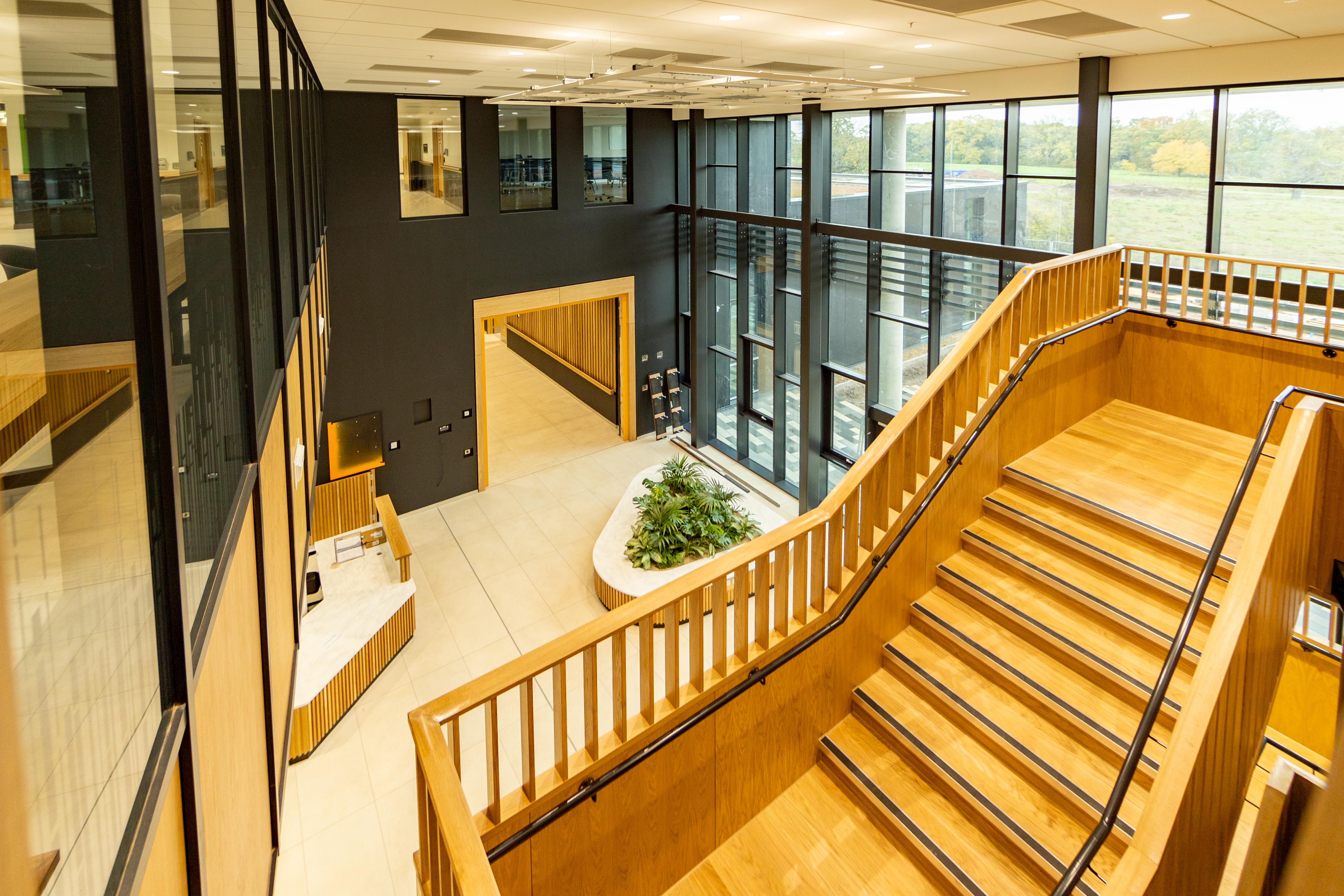 Interior of the National Rehabilitation Centre with wooden stairs and a green plant installation.