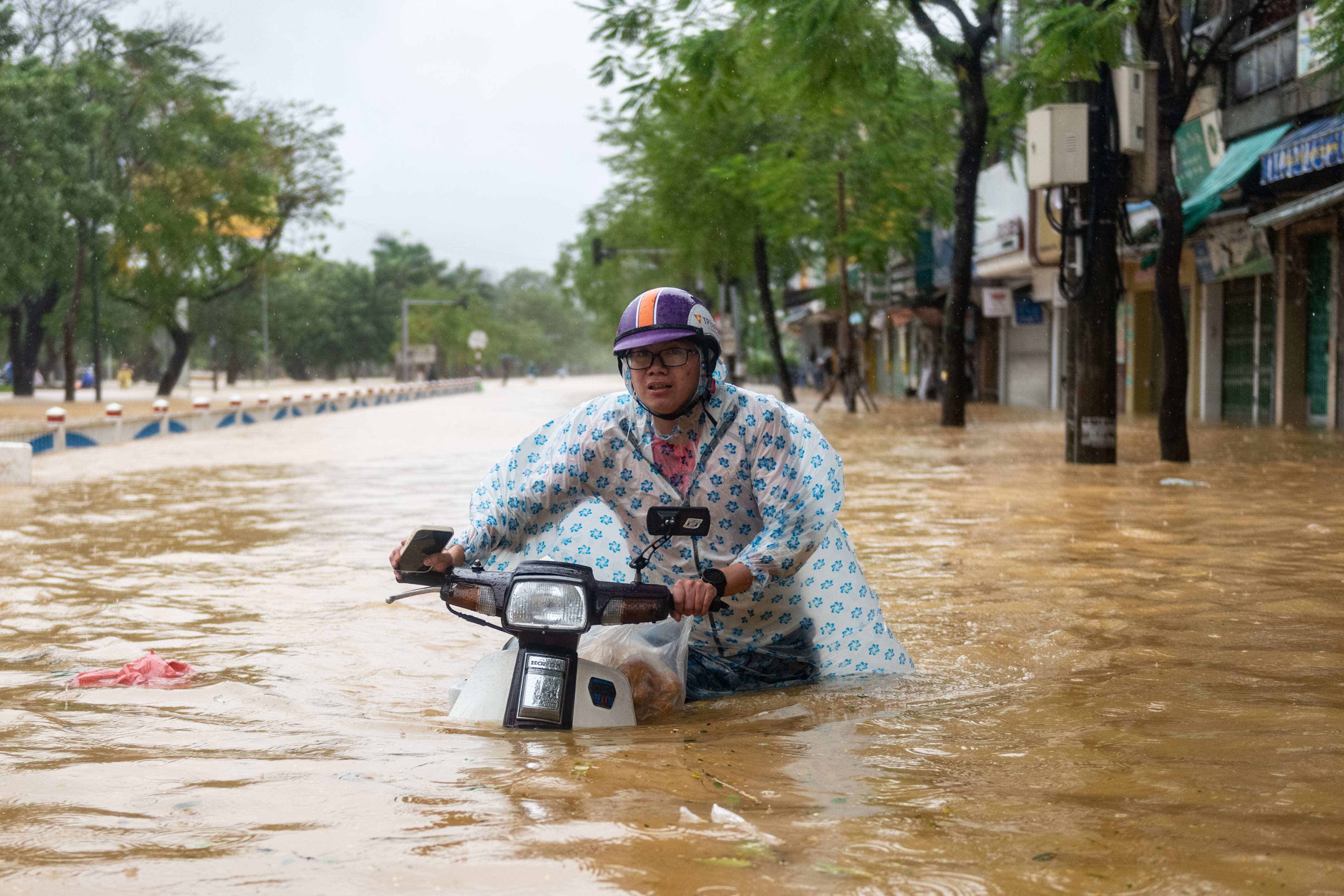 A person on a scooter rides through deep floodwaters in Hue, Vietnam.