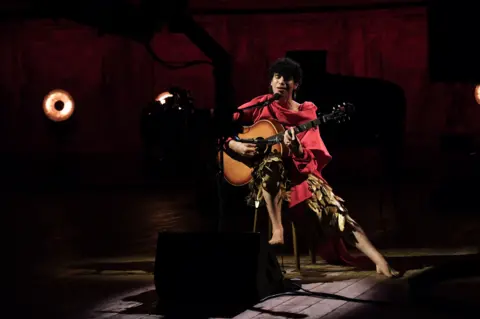 Jacob Alon closes their eyes and sings passionately into a microphone while appearing on the BBC's Later... With Jools Holland