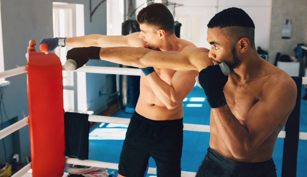 Two men punch in a boxing gym.