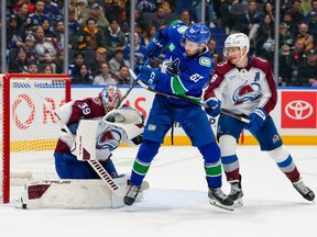 Mackenzie Blackwood makes a save as teammate Cale Makar defends against Max Sasson during the first period