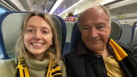 BBC Kate with her father Mark on the train on their way to a Wolverhampton Wanderers football match wearing the merch scarf
