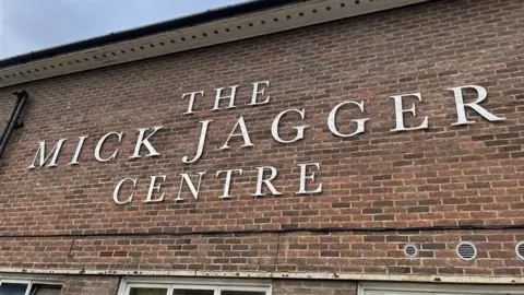 Phil Harrison/BBC A brick wall adorned with silver letters that read The Mick Jagger Centre.