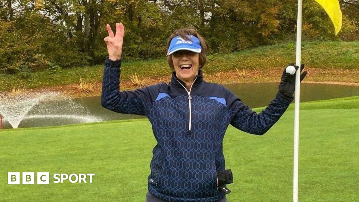 Lyn Parry holds up three fingers and a flag to celebrate her hole-in-one treble success
