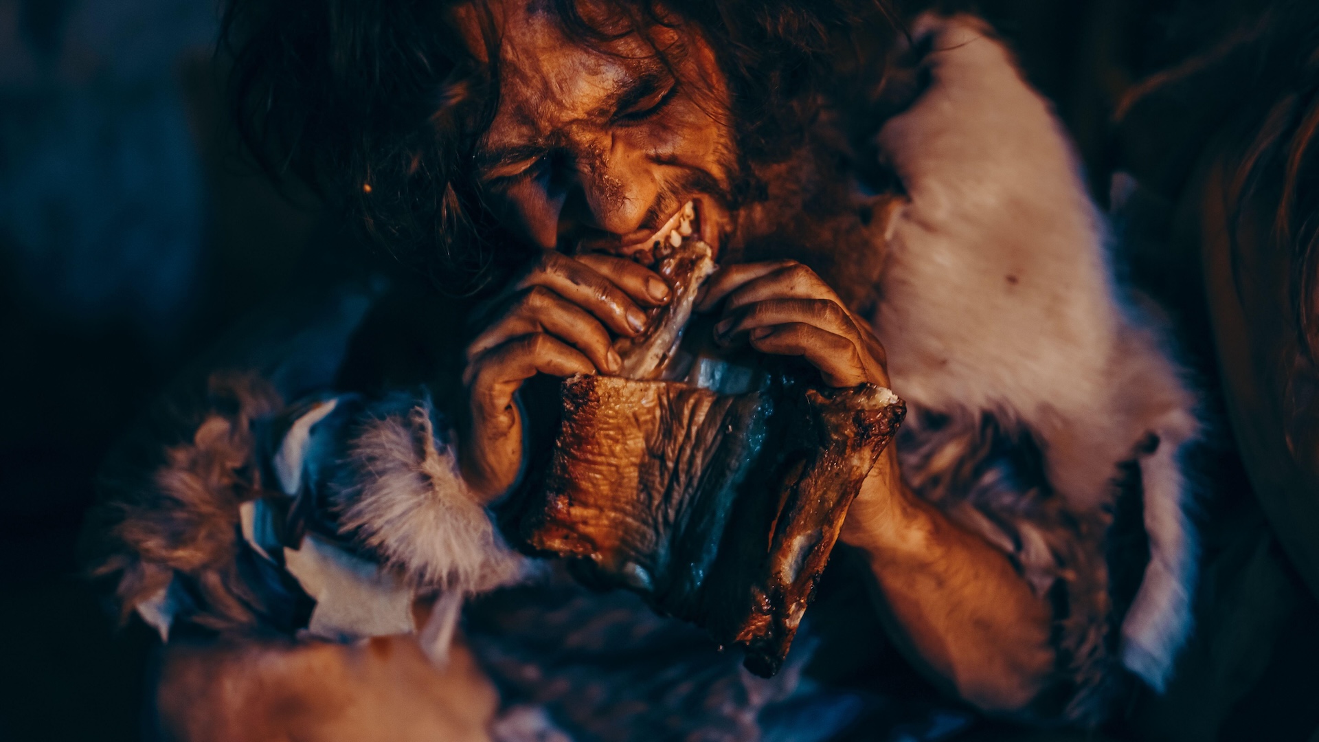 a recreation of a neanderthal man eating a hunk of meat