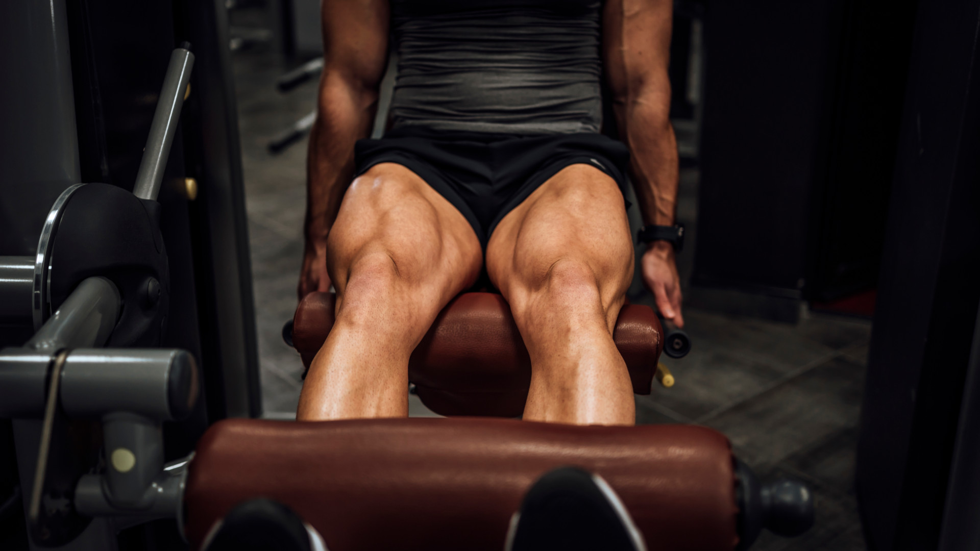 A man with muscular quads using the leg extension machine