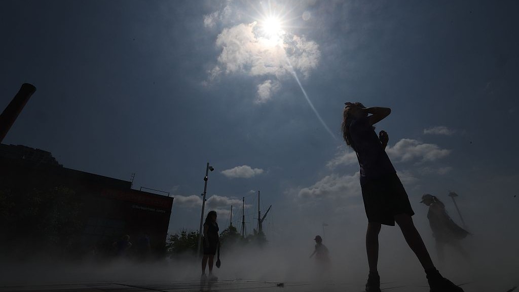 People cooling off under high sun at a cooling pad in Toronto.