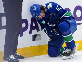 Quinn Hughes holds his arm and kneels on the ice after getting tangled up with Winnipeg Jets' Mark Scheifele, not seen, during the second period on Tuesday night