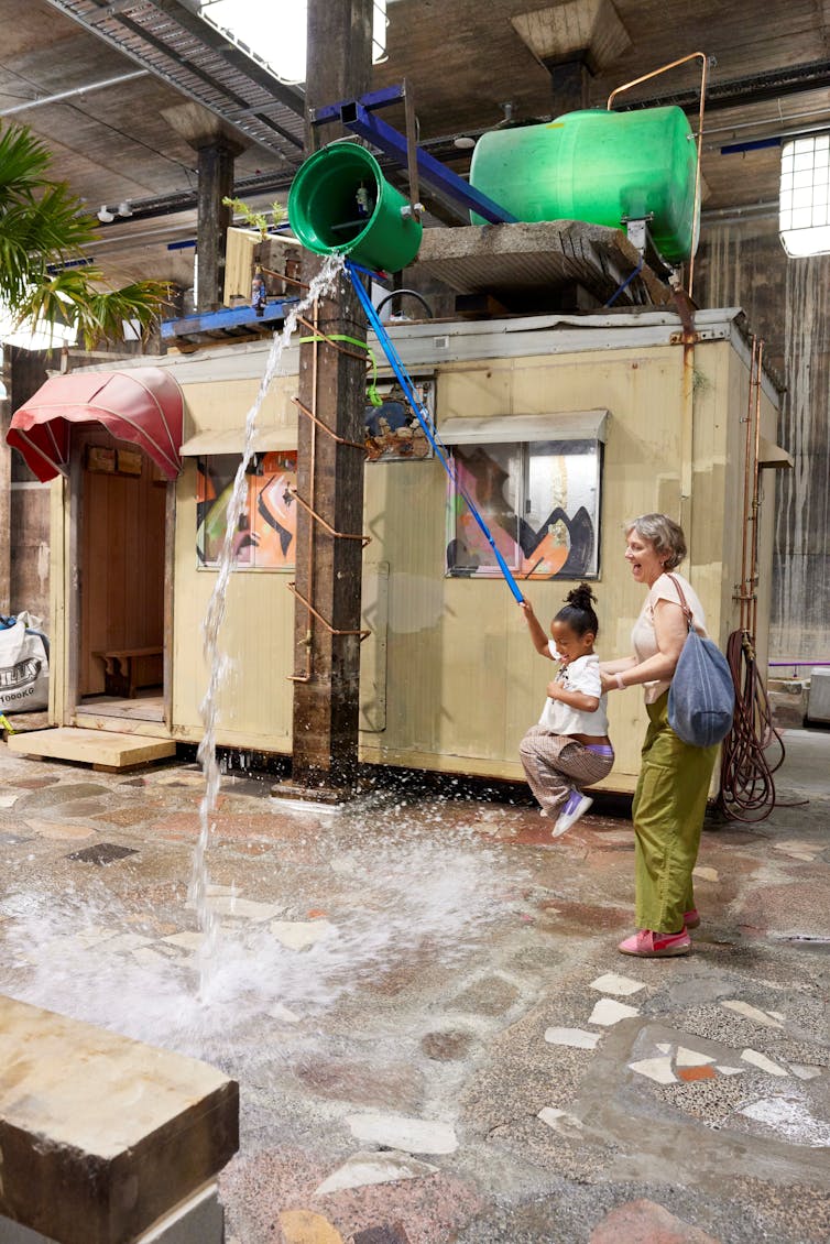A kid swings while a bucket drops water.