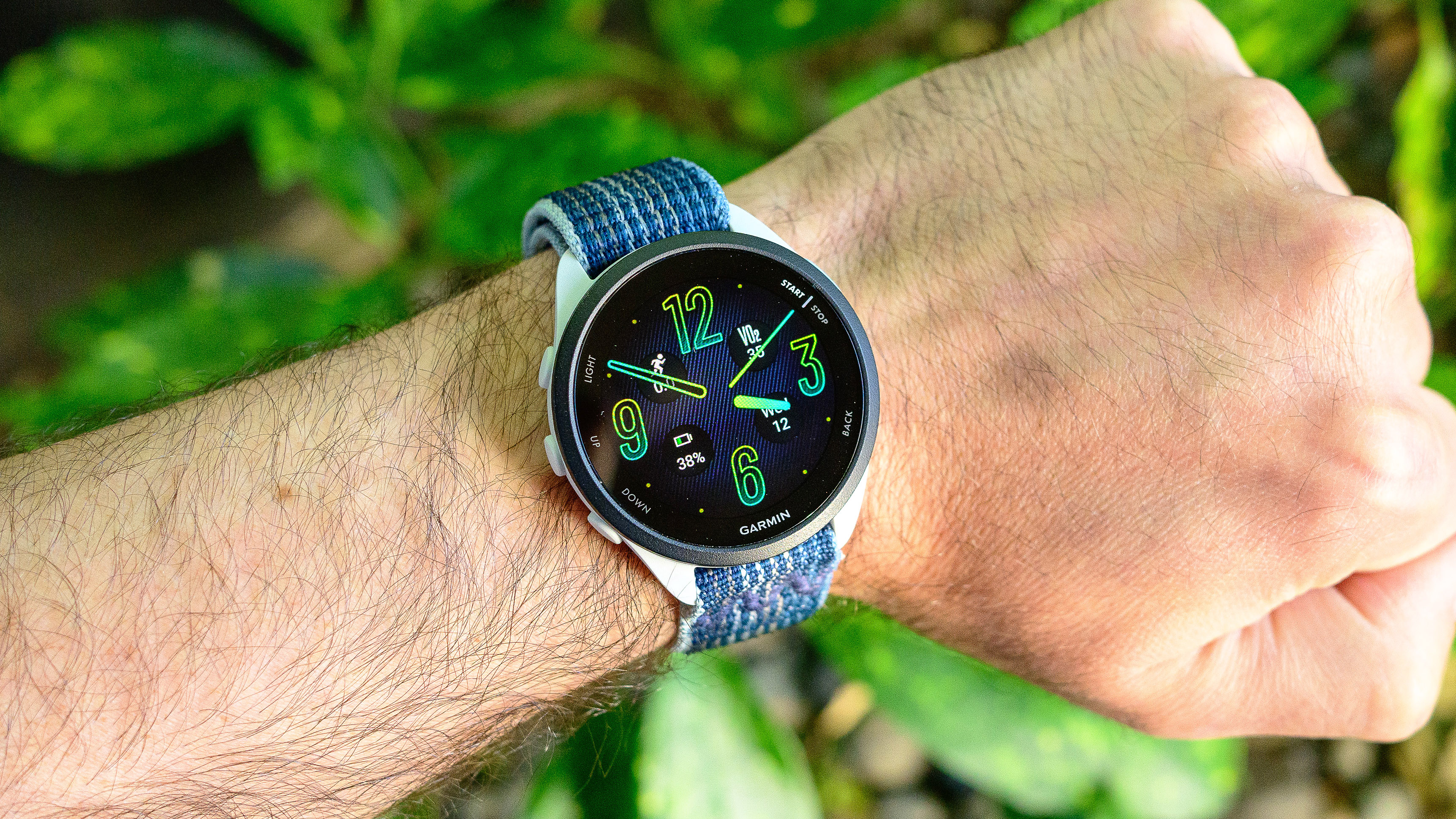 The Garmin Forerunner 165 GPS watch on a user's wrist with a blue woven band attached