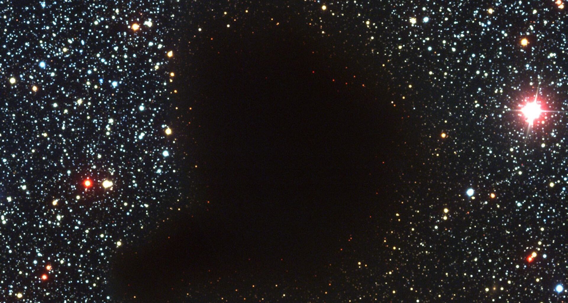 a photograph of starry outer space with a dark blob in the middle