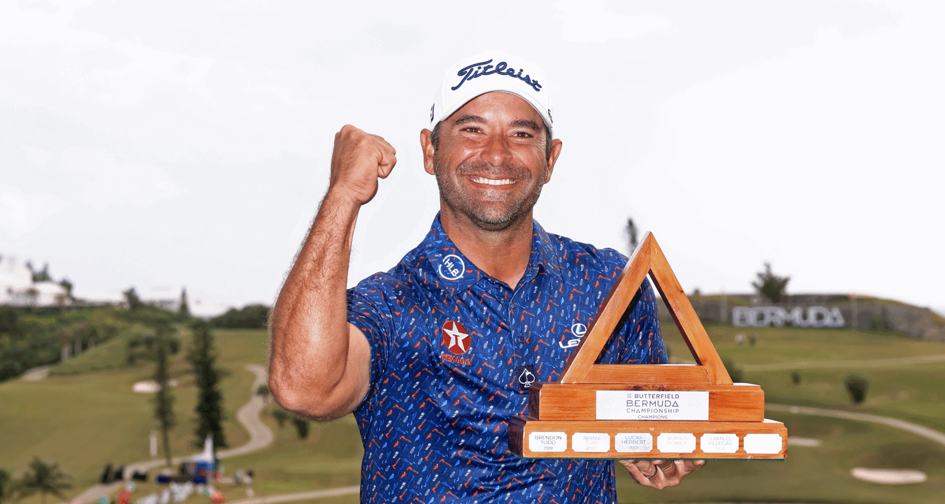 Rafael Campos punches the air while holding the Butterfield Bermuda Championship trophy in 2024