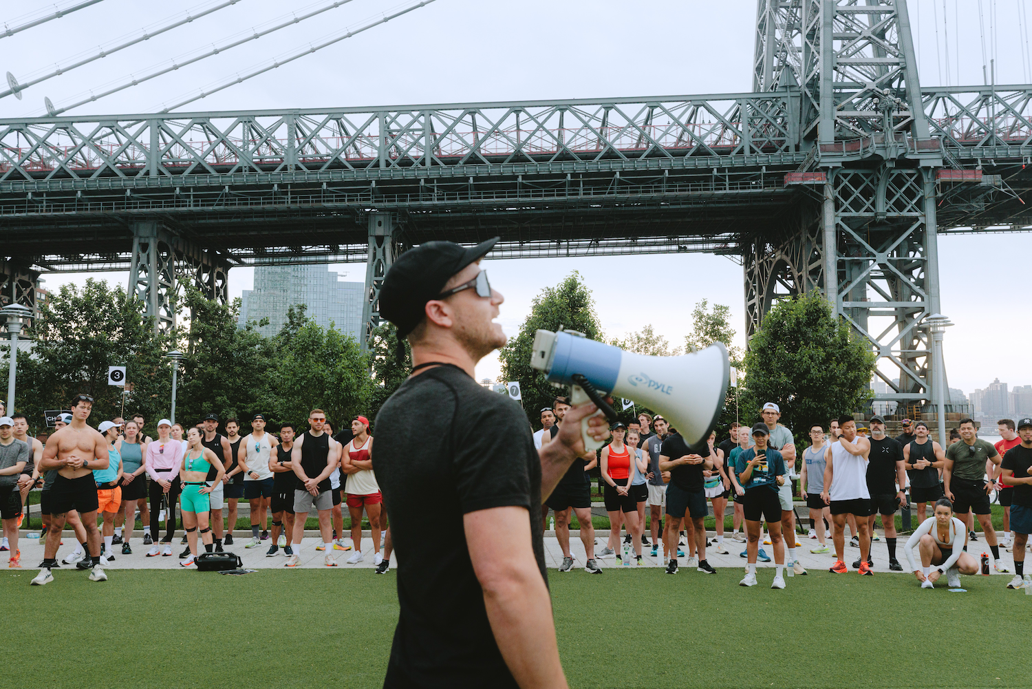 A man speaks into a bullhorn as competitors gather at the start line. 