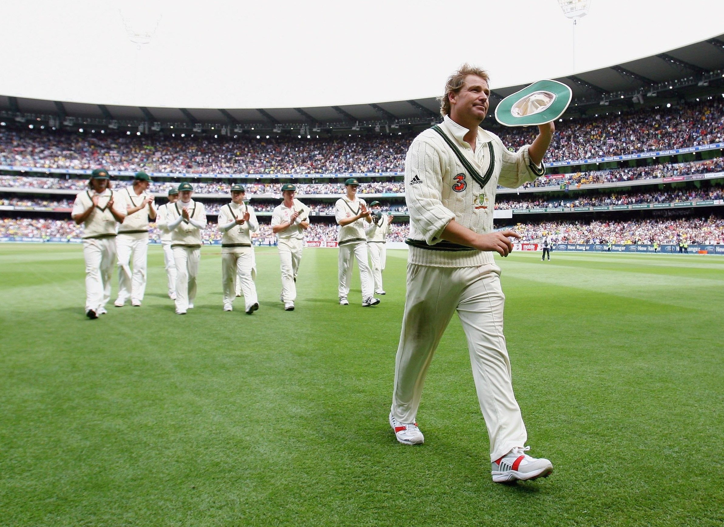 Shane Warne holding up his hat to a stadium full of fans after taking his 700th test wicket.