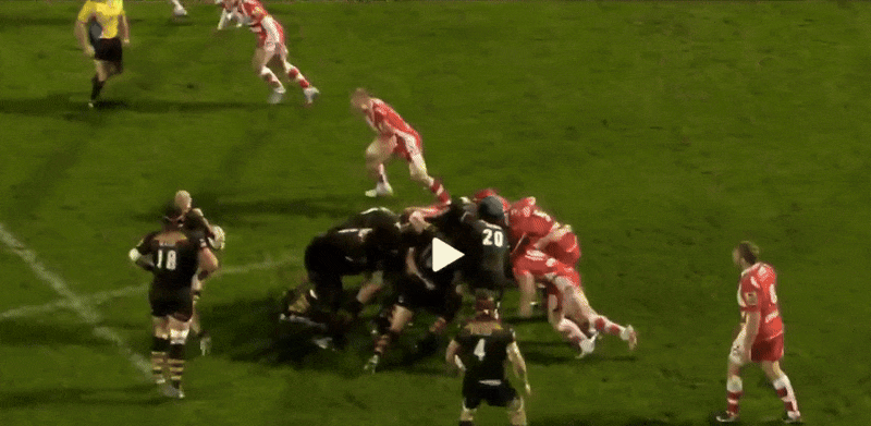 Rugby players in black and red jerseys forming a scrum.