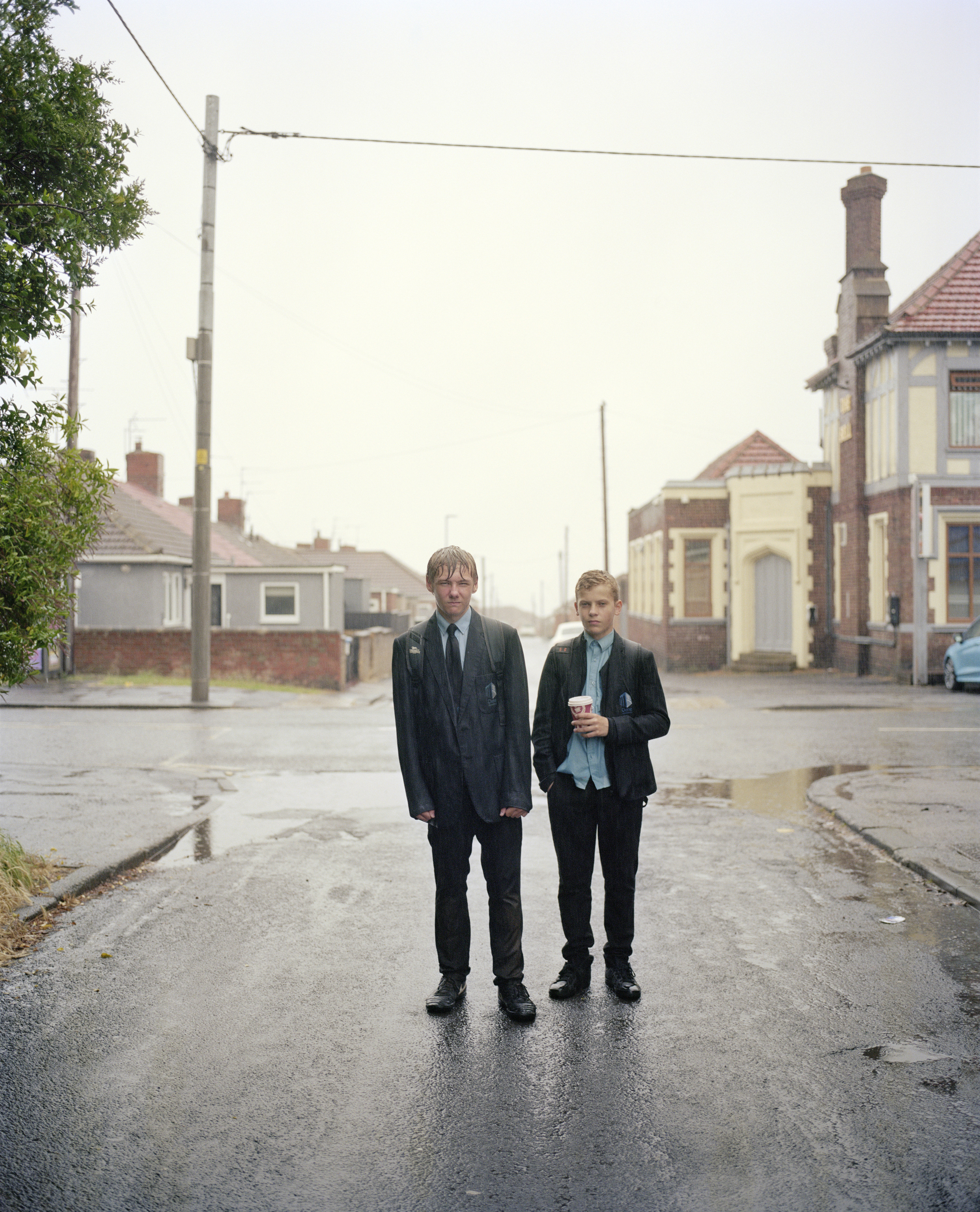 Jacc and Morgan standing on a wet street in the rain.