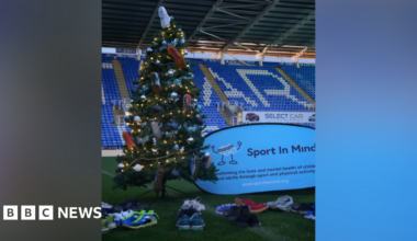 A Christmas tree decorated with trainers on the pitch in front of the stand at Reading FC's stadium