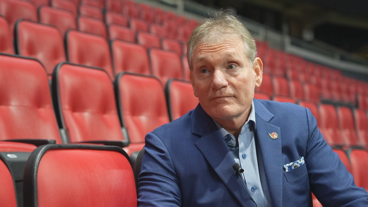 A man sits on a red chair.