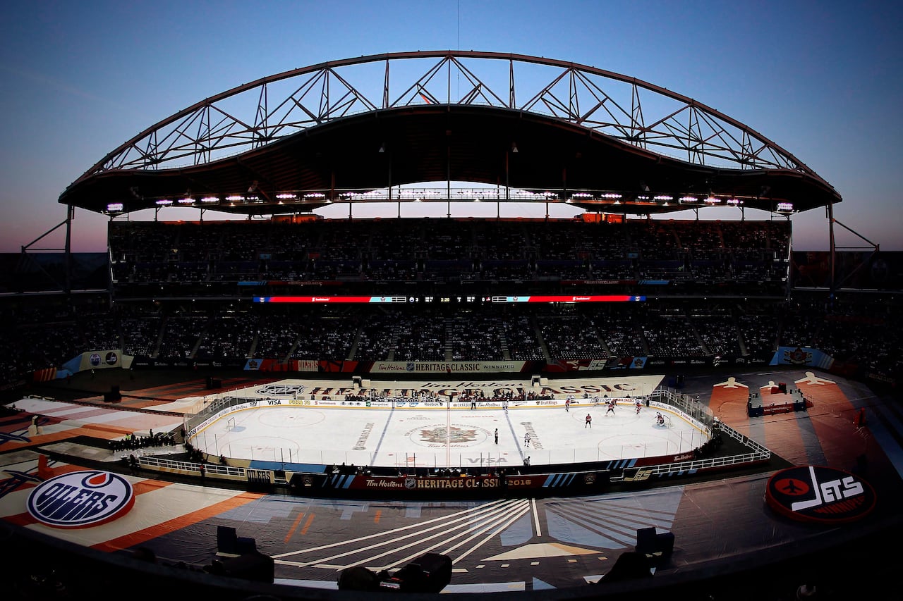 An outdoor hockey rink is seen from above, set up in a football stadium.