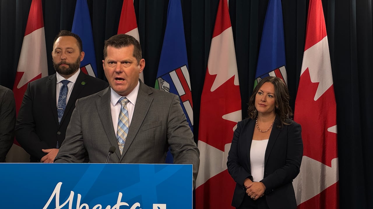 A group of people stand behind a podium that reads Alberta.
