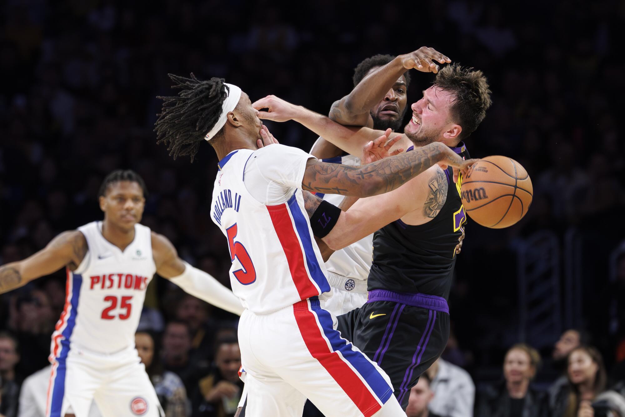 Lakers guard Luka Doncic, right, inadvertently hits Detroit Pistons forward Ronald Holland II in the face.