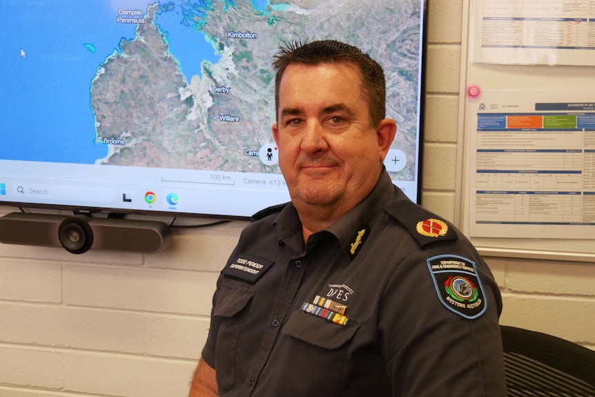 middle-aged man with short grey hair and DFES uninform posing in front of a map