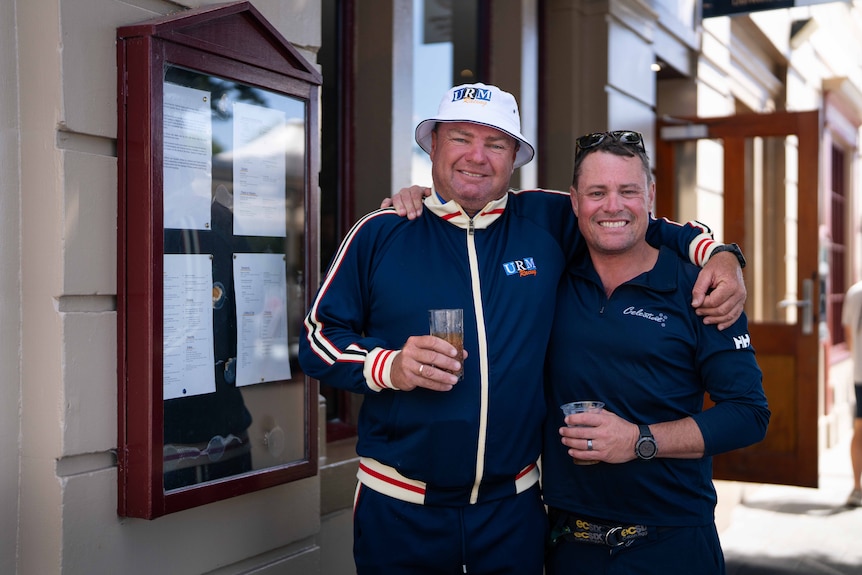 Two men smiling for a photo, holding beer