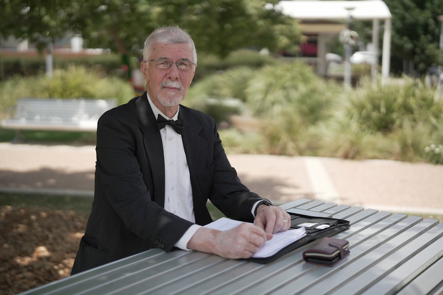 Michael Sanderson sits at a table in a park.