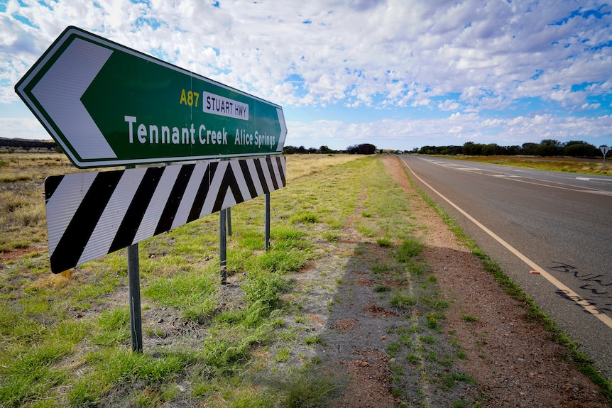 A traffic sign on a highway pointing to Tennant Creek in one direction and Alice Springs in the other.