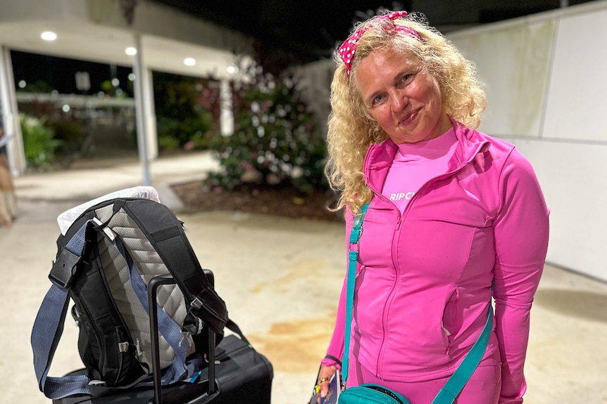 A woman in pink with a backpack beside her. 