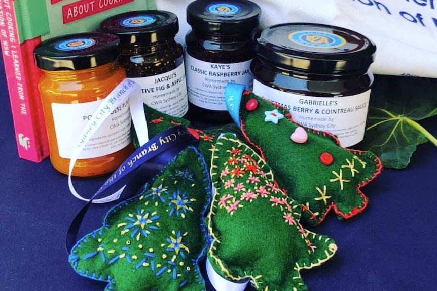 Handicraft christmas trees and jams on a table with a sign near it saying 'Country Women's Association'.