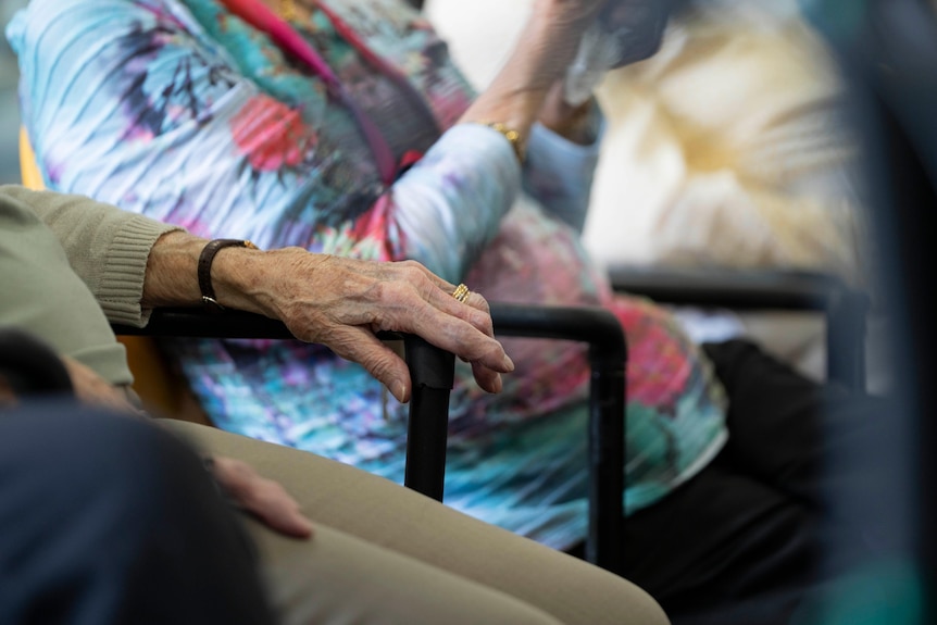 Close up of elderly person's hand on a chair.