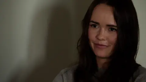 Moose Campbell/BBC Irena Terekh from Fire Point with an off white background, long black hair and grey jumper