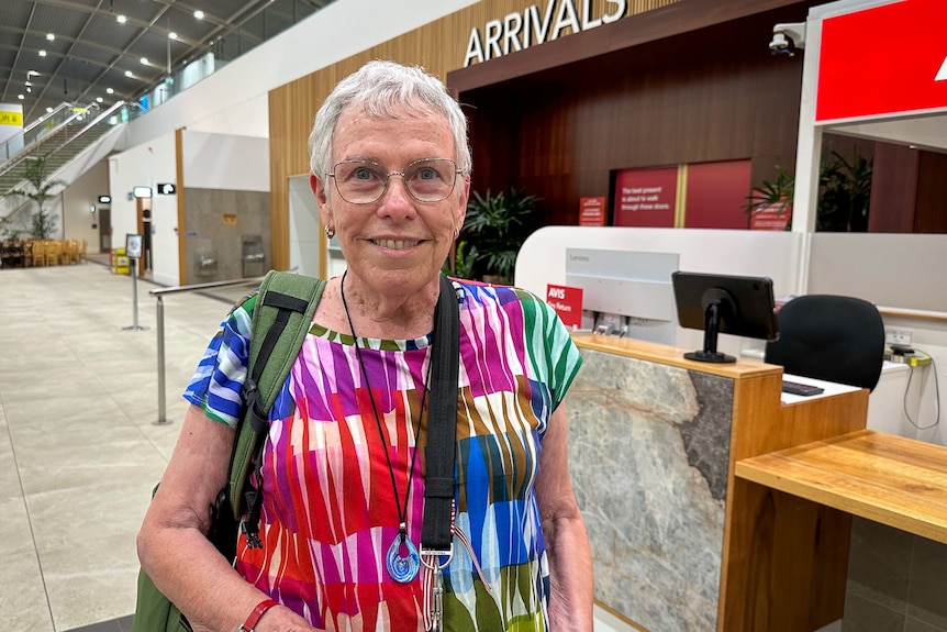A woman in a tie dyed shirt smiles. 