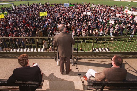 Then Prime Minister John Howard (centre) addressing the gun rally at the Sale Football Club Victoria wearing a bulletproof vest, flanked by his bodyguard (right) and Local Federal Member Peter McGauran (left).