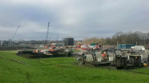 Photograph of Bury waste water treatment works. The image shows cranes and maintenance work taking place in the sewage beds.