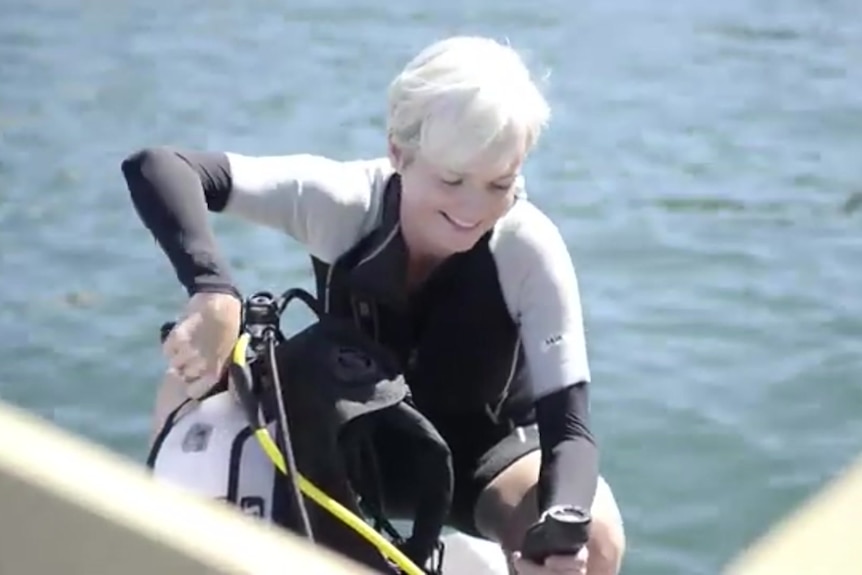 Emma Johnston smiles while coming out of the water while wearing a wesuit.