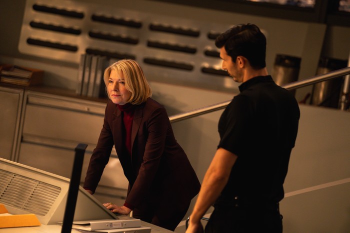Jemma Redgrave as Kate Stewart and Alexander Devrient as Colonel Ibrahim in Doctor Who. Kate is leaning over a desk in UNIT HQ, with the Colonel looking at her.