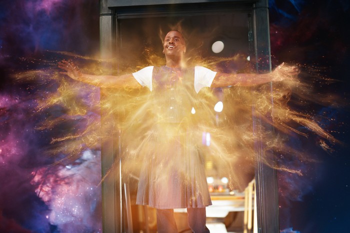 Ncuti Gatwa as The Doctor in Doctor Who. He is stood on the edge of the TARDIS doors, which is floating in space, with his arms out as his character regenerates, with his chest engulfed in a yellow glow