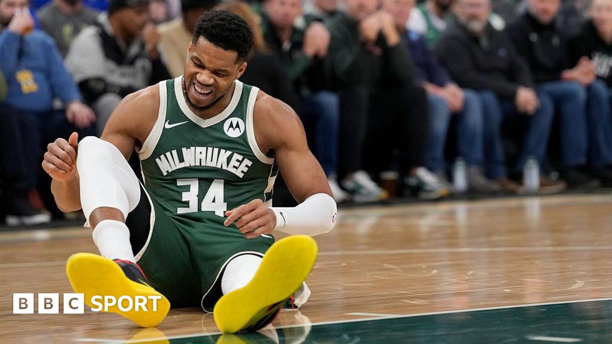 Giannis Antetokounmpo sits on the floor of the court with a pained expression on his face after picking up an injury