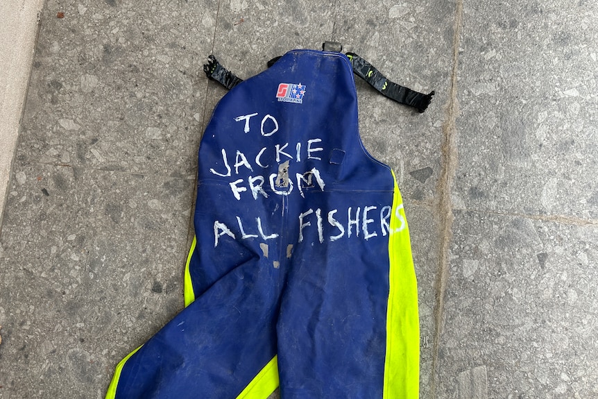 Blue fishing overalls with writing on them. 