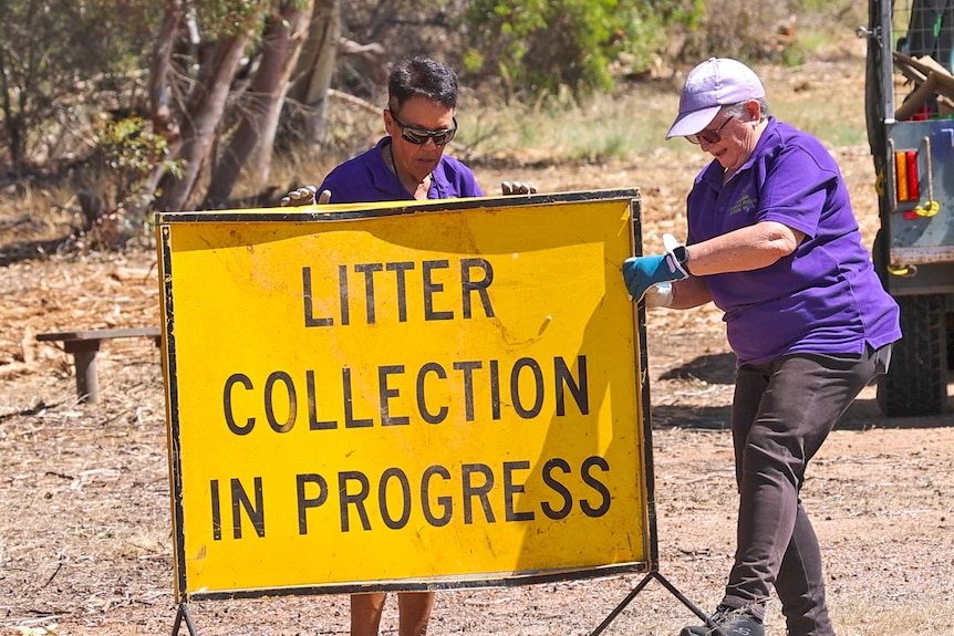 Sherry Martin and Glenda Green put a "litter collection in progress" sign up along the side of a highway.