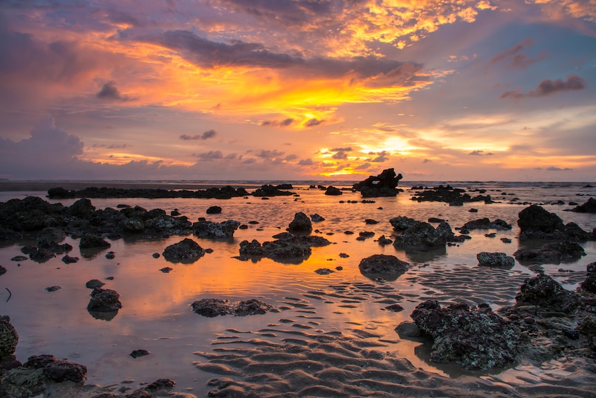 A sunset over a shallow coastal beach near Darwin, NT.