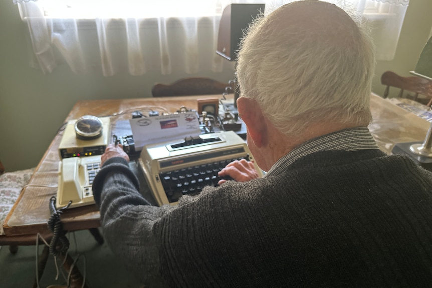 A shot from behind of a man's head typing a letter on a typewriter