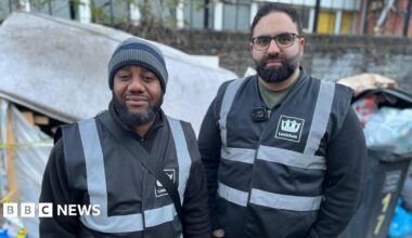 Alain N'Guessan Bi and Eiman Rostami wearing dark Lewisham clothing. They are standing in front of overfilling bins and a stained mattress