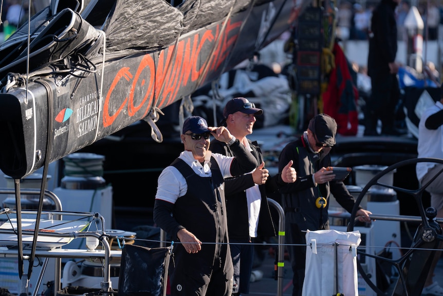 two men on a boat smile and give thumbs up