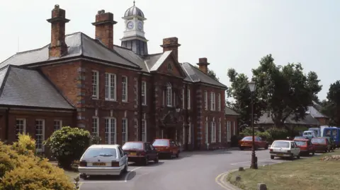 Historic Hospitals / Dr H Blakeman The front of a hospital. There are cars parked outside. 