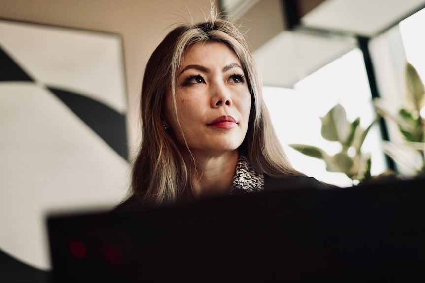 Woman with dark hair with blonde highlights looks past camera