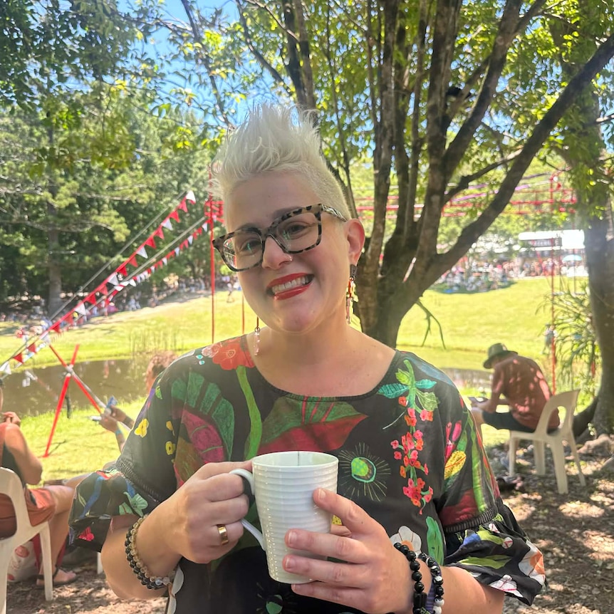 Lady holding a cup of tea smiling at the camera