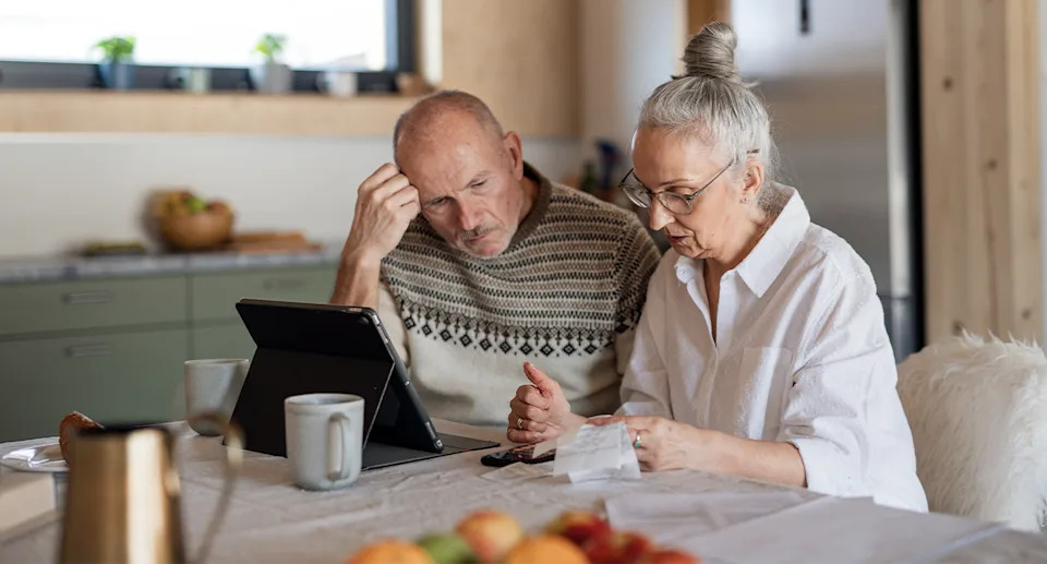 An older couple sits at a dining table.
